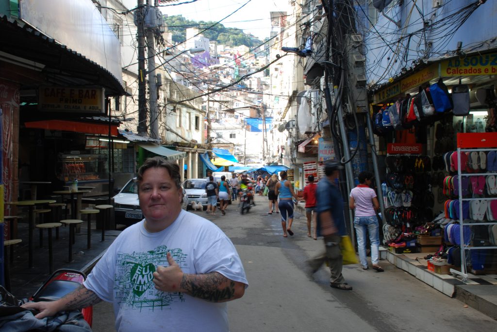 A person giving a thumbs up in a busy street.