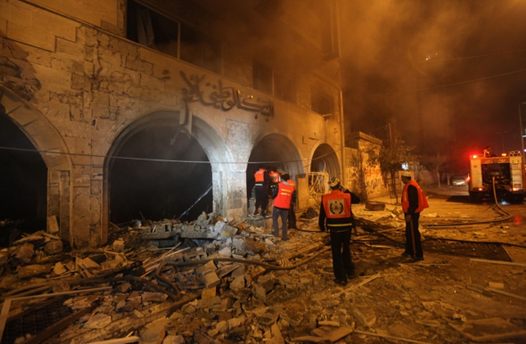 Palestinians try to extinguish a fire in a branch of the Islamic National Bank after an Israeli air strike in Gaza City