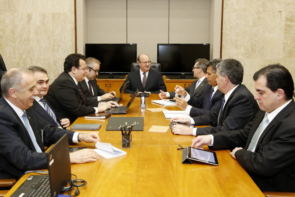 Men in suits at a conference table with laptops