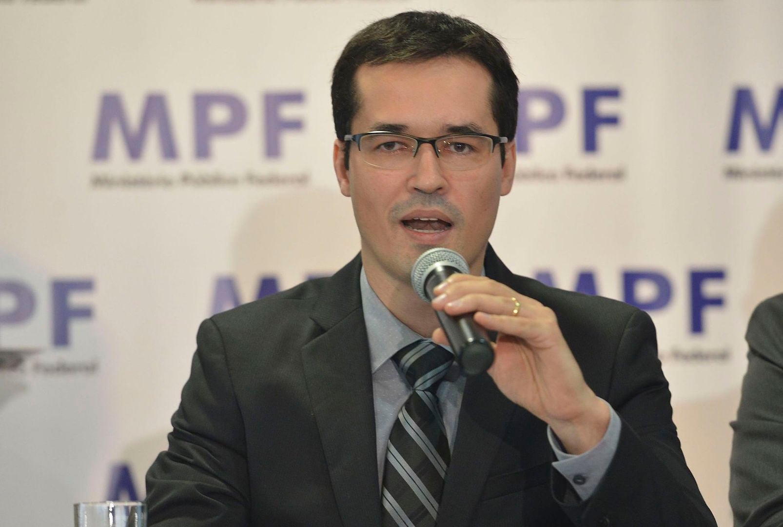 Deltan Dallagnol speaking into a microphone in front of a federal prosecution service backdrop