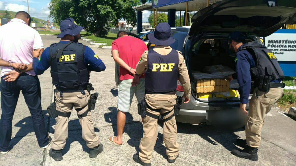 Federal Highway Police officers beside a car boot packed with drug parcels in Rio de Janeiro state