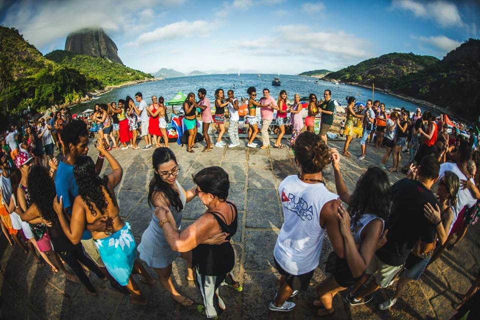 People dancing salsa in pairs on an open-air terrace in a crowd