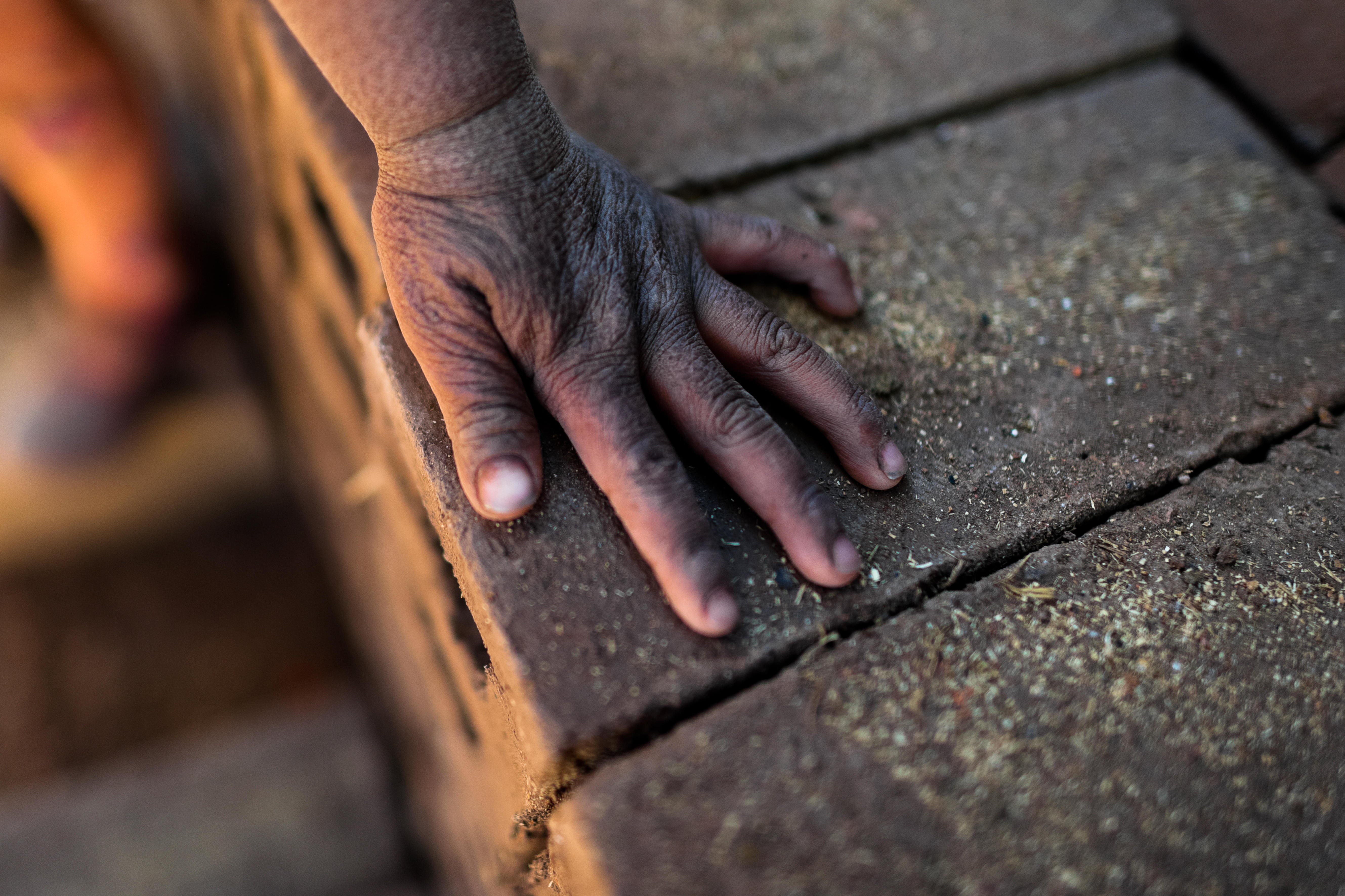 A sunburned hand of a young girl worker is seen on a pile of bricks at a brick factory in the outskirts of Puno, Peru.
