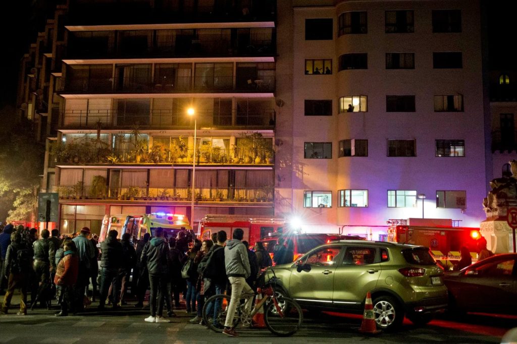 Onlookers look at the building where six Brazilians died in an apartment of apparent carbon monoxide poisoning in Santiago