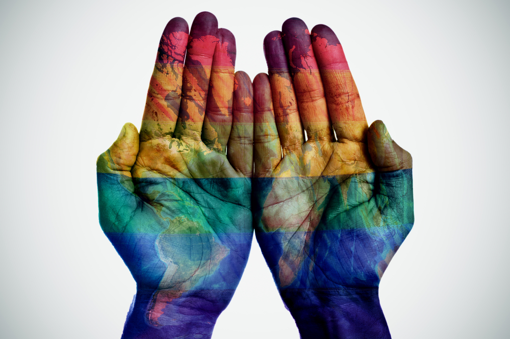 world map and rainbow flag in the hands