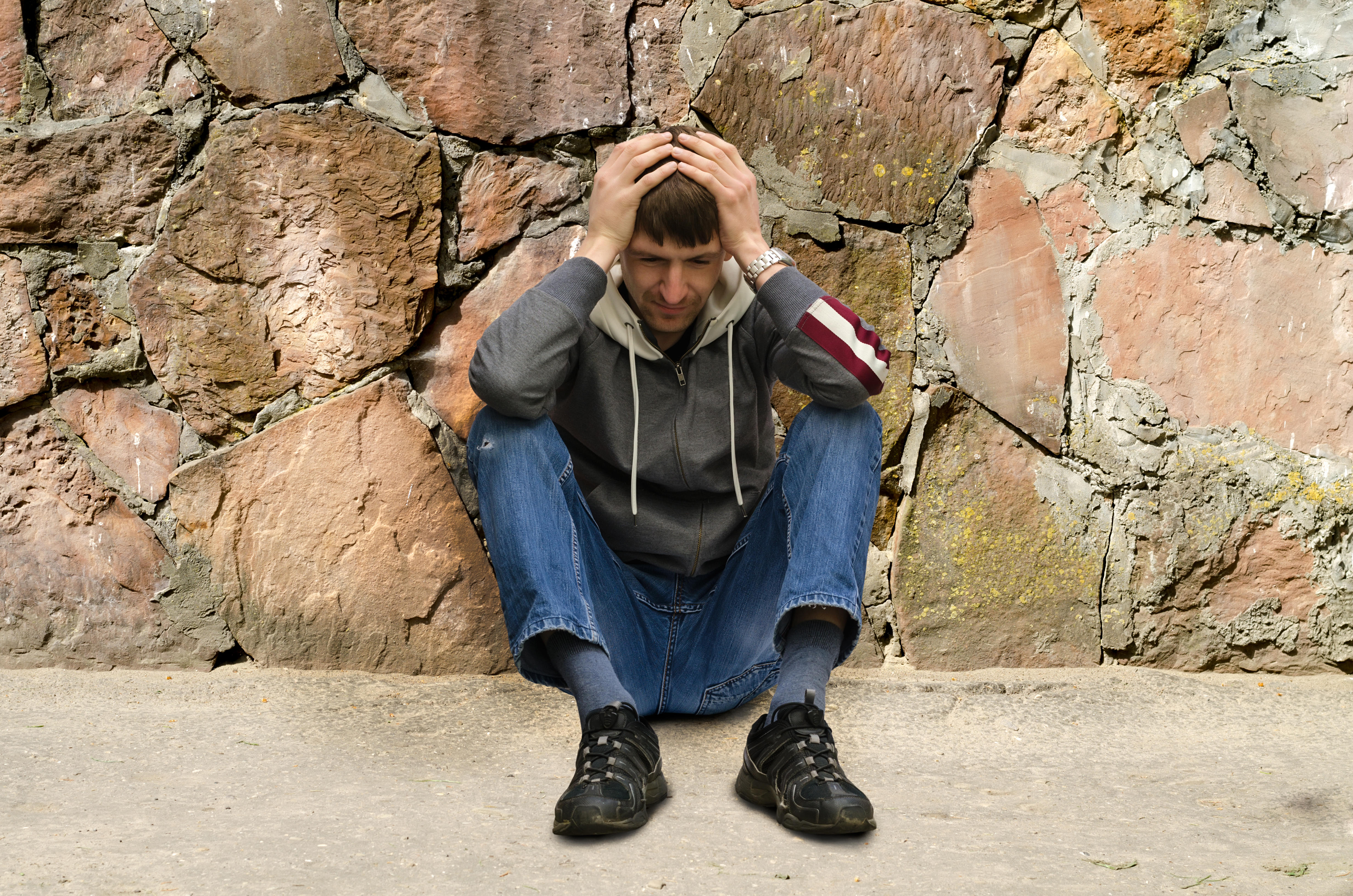 sad man sits on the sidewalk