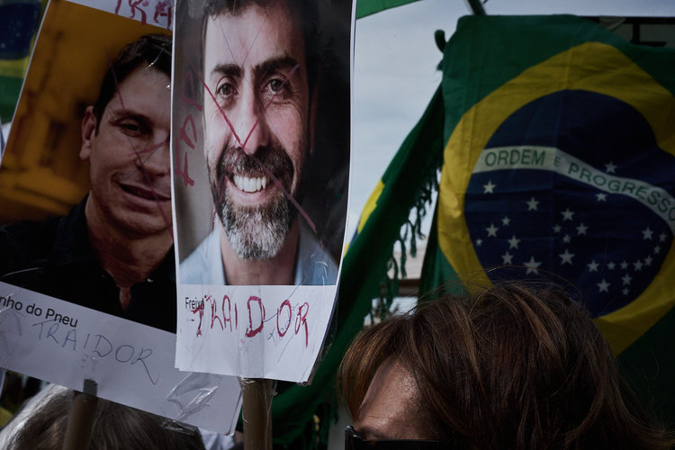 A woman holds up a sign showing the face of politician Marcelo Freixo with the word "Traitor" written across his face (Photo: C.H. Gardiner)
