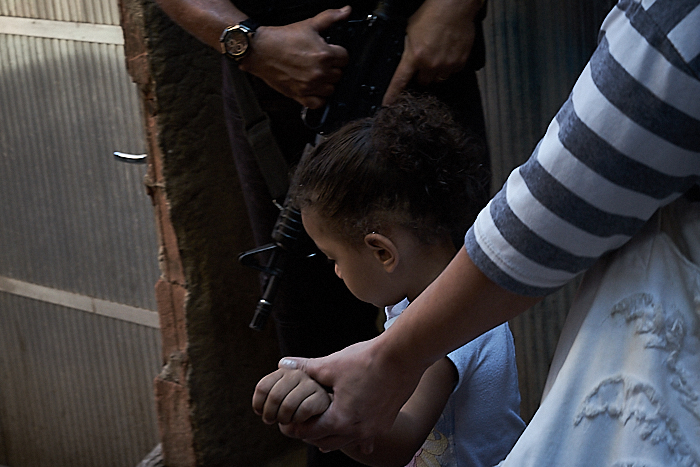 A woman walks with her child past police in Rio de Janeiro. (Photo: C.H. Gardiner)