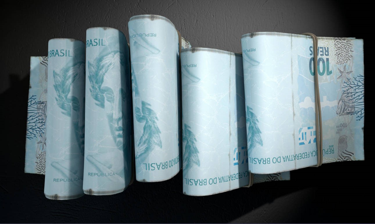 A close-up view of five wads of folded over stacks of brazilian real banknotes each bound informally by a rubber band set out