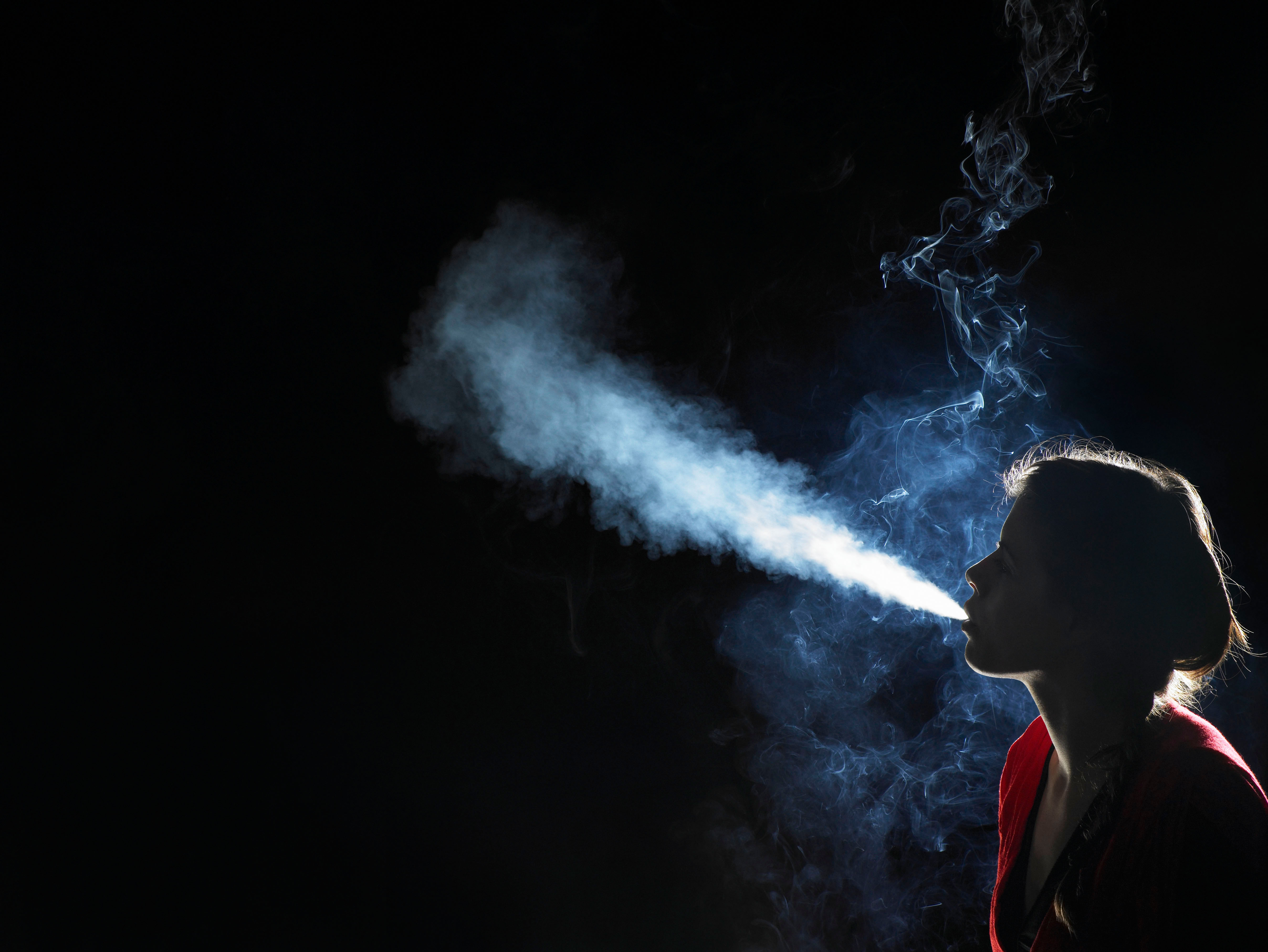 Young woman blowing out smoke