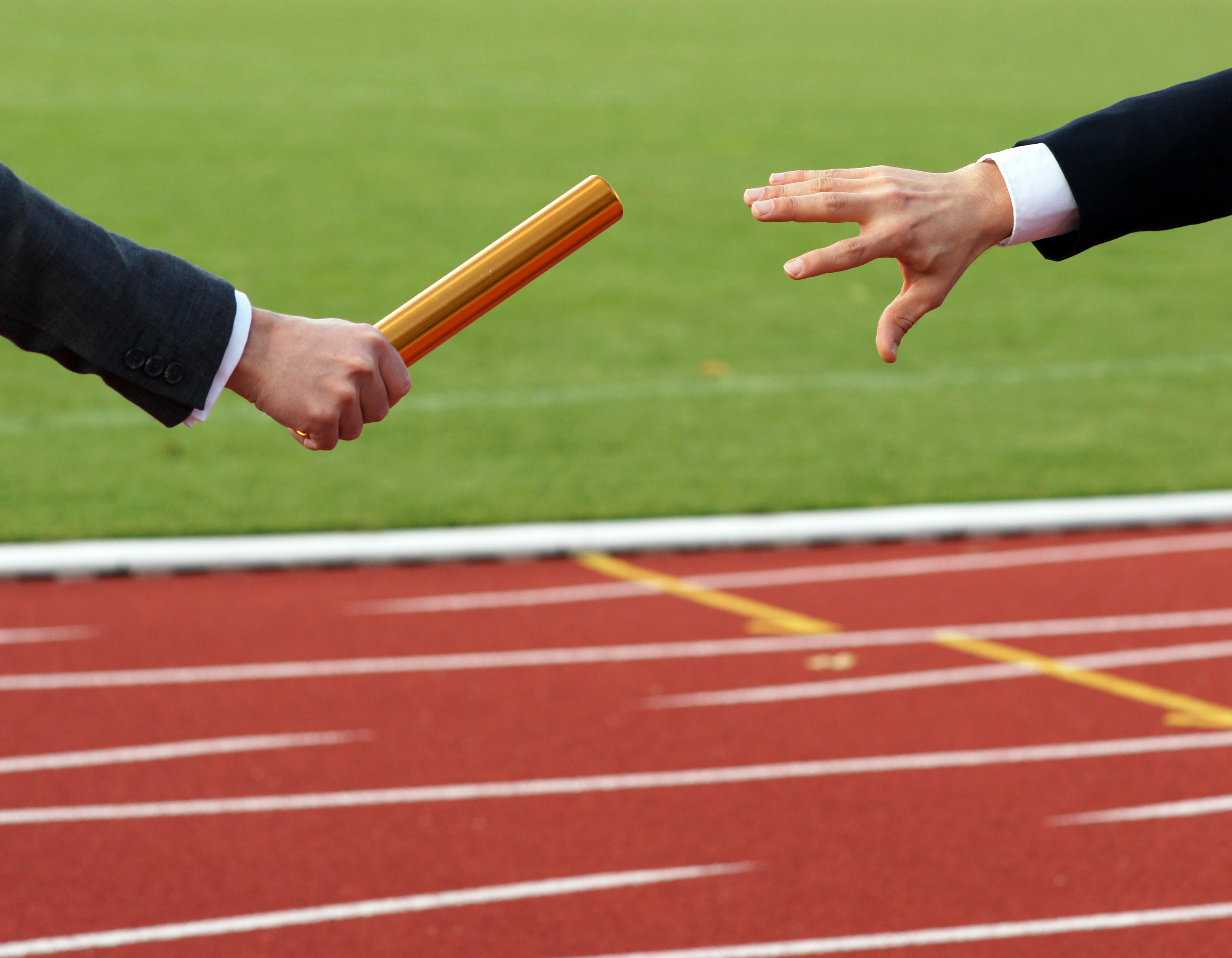 Businessman passing baton in relay race outside in stadium - concept succession business cooperation