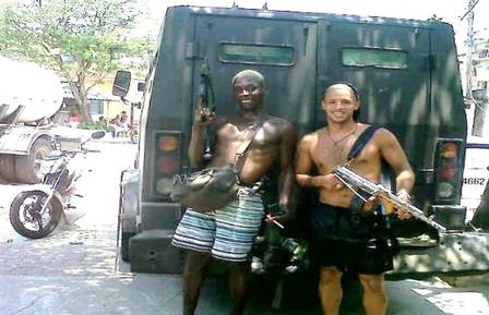 Armed traffickers pose next to an armored vehicle used by police. (Photo: Police Release)