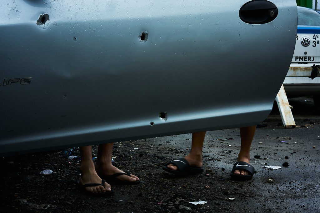 Residents of mangueira inspect damage to their car, hit by bullets during an attack on a local police base. (Photo: C.H. Gardiner)