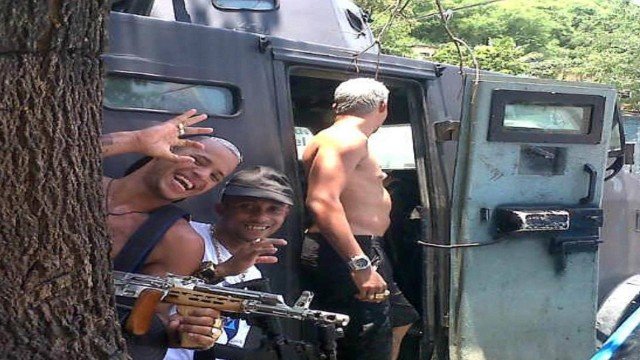 Armed traffickers pose next to an armored vehicle used by police. (Photo: Police Release)