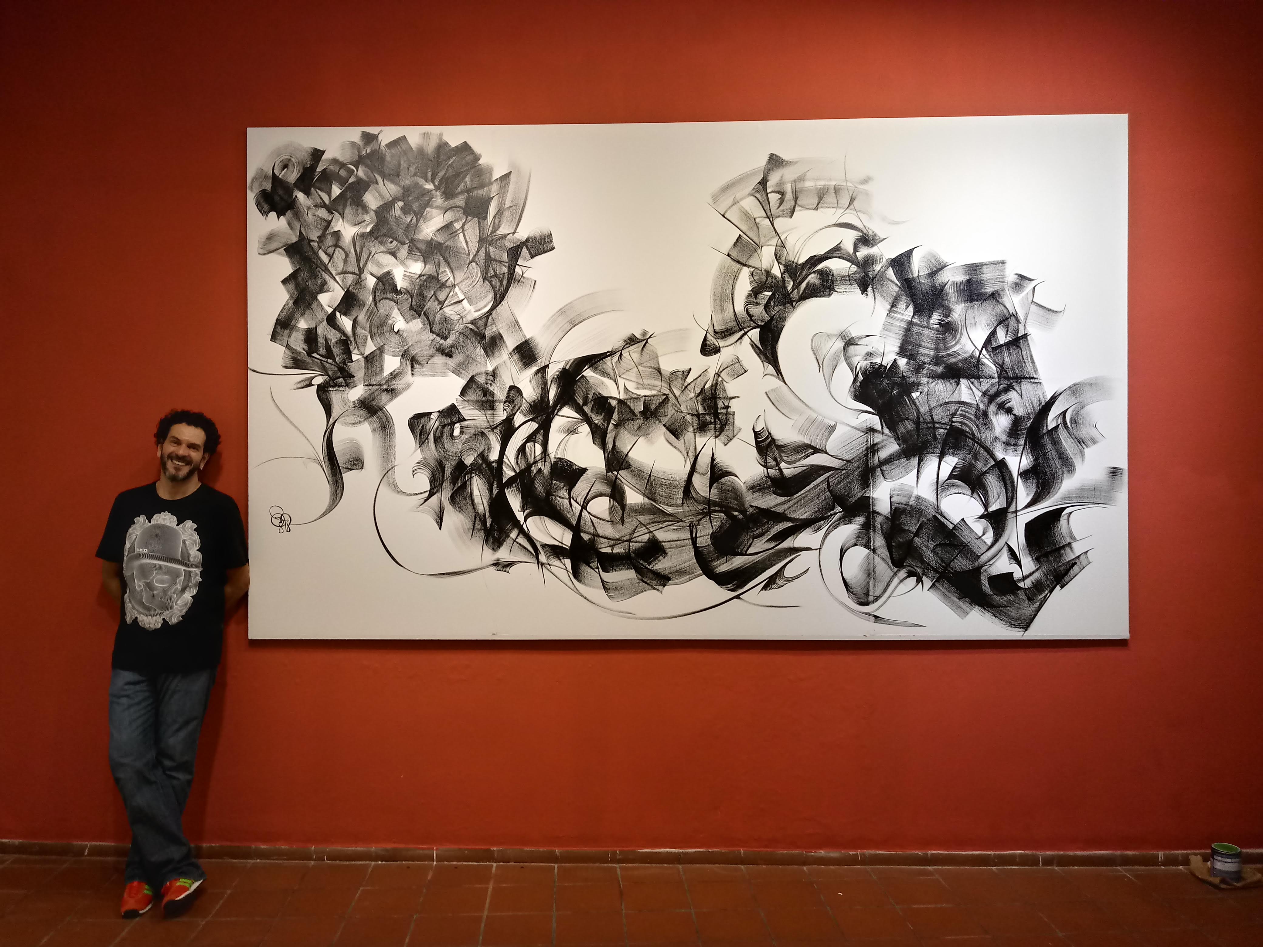 Artist Claudio Gil next to one of his works.