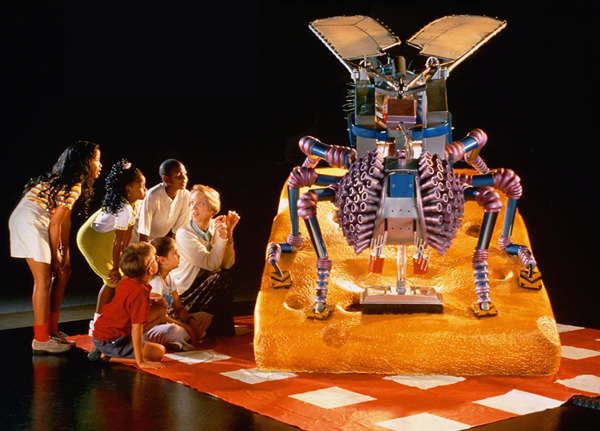 A domestic fly with 3-meter wings feeds on a slice of cheese on a table. Its head rotates and waves in several directions as its wings move.