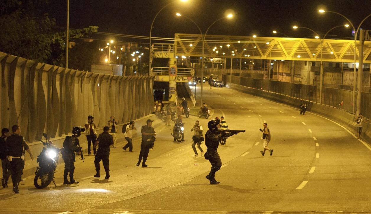 Policemen take positions during a shooting with suspected drug gangs after a protest at Linha Amarela highway near the slum complex of Mare in Rio de Janeiro