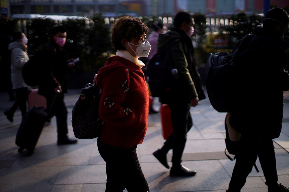 Passengers wearing masks walk at the Shanghai railway station