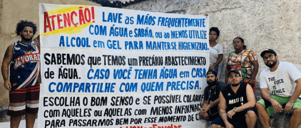 Members of Coletivo Papo Reto holding one of their banners with preventative information. Photo - Voz das Comunidades