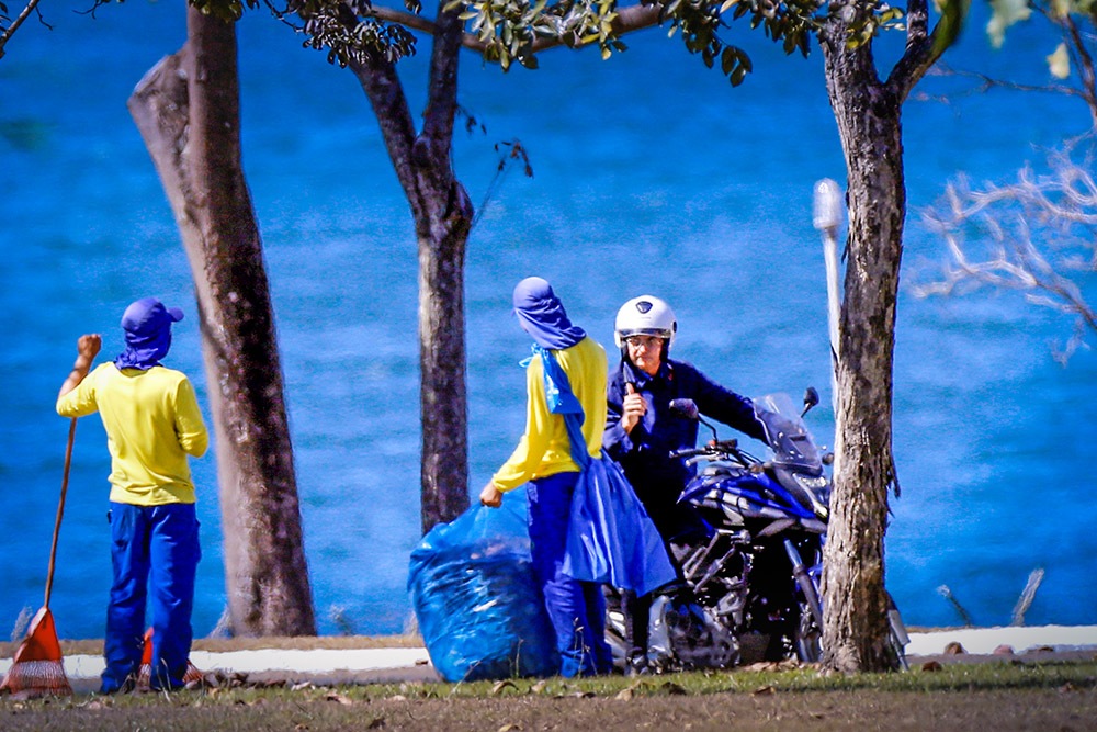 Brazilian President Jair Bolsonaro talks to street sweepers during a motorcycle ride at the Alvorada Palace.