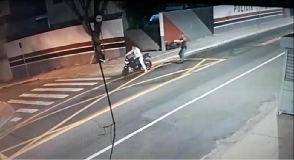 The first shot occurs when the motorcycle was stationary and the man had his back to the police officer, getting off the vehicle.
