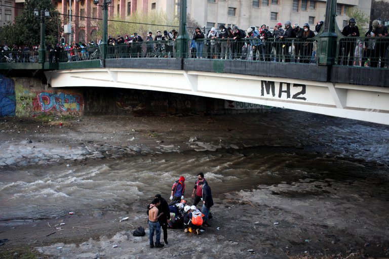 The 16-year-old fell from the Pio Nono bridge, at least five meters above the almost dry bed of the Mapocho River, during a protest around Santiago's Plaza Italia on Friday when a group of protesters was being chased by police troops.