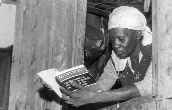 Carolina Maria de Jesus by the window in her house, probably in the favela of Canindé, in São Paulo, reading a book from an English course. Photo- UH_Folhapress.jpg