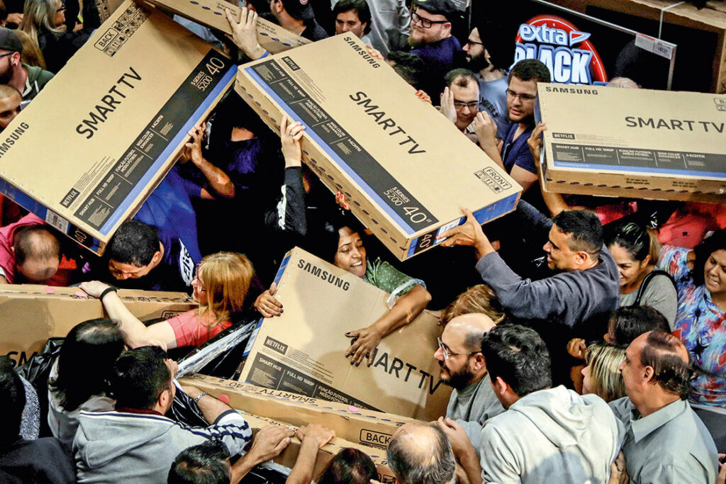 Shoppers reach out for television sets as they compete to purchase retail items on Black Friday at a store in Sao Paulo