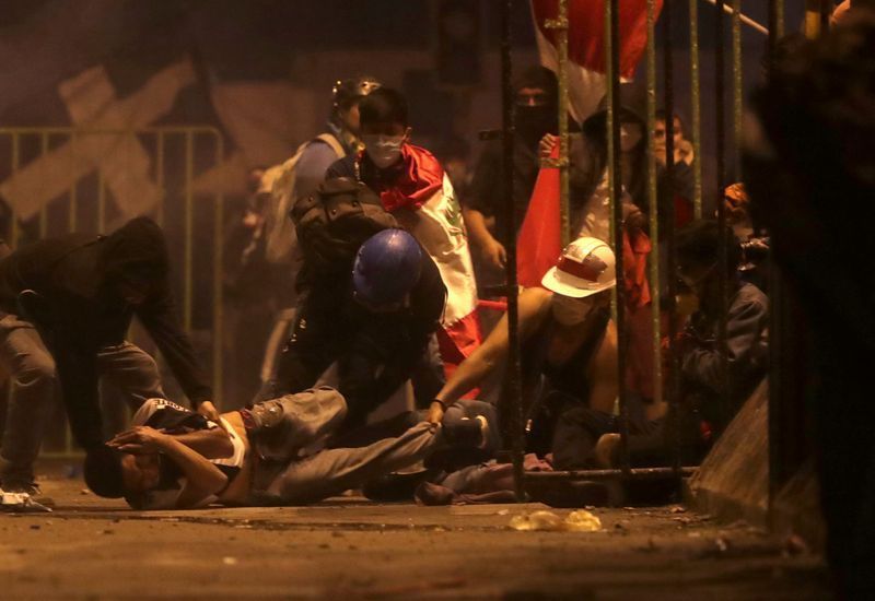 FILE PHOTO: A demonstrator is injured on the ground as he is help by other demontrators during a clash with police during a protest against the decision of Congress to remove former President Martin Vizcarra, in Lima