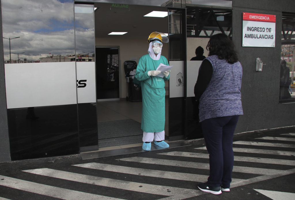 Healthcare worker talking to person outside hospital entrance