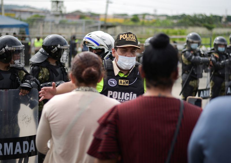 Family members of inmates argue a police officer outside a prison where inmates were killed during a riot that the government described as a concerted action by criminal organisations, in Guayaquil
