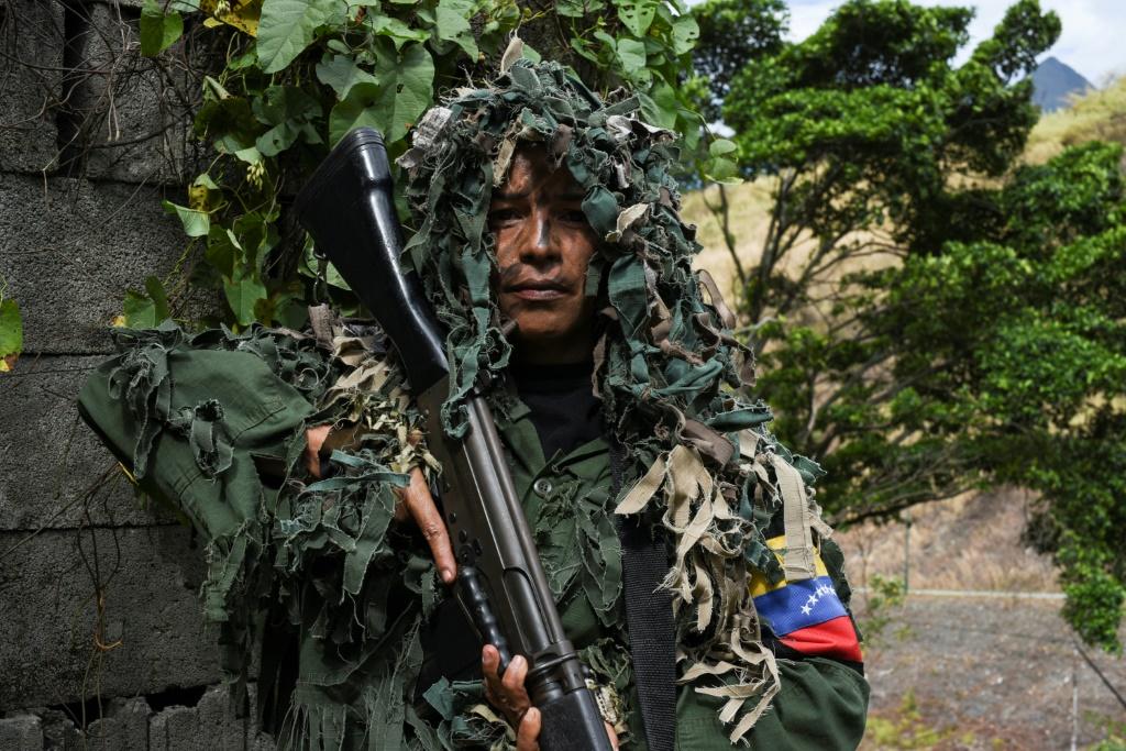 Ismaira Figueroa holds her position on a hill, rifle in hand, as she takes part in military exercises simulating an invasion.