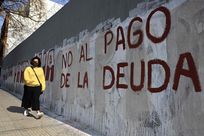  A woman passes in front of a graffiti against the payment of the debt, in Buenos Aires. (Photo Internet Reproduction)