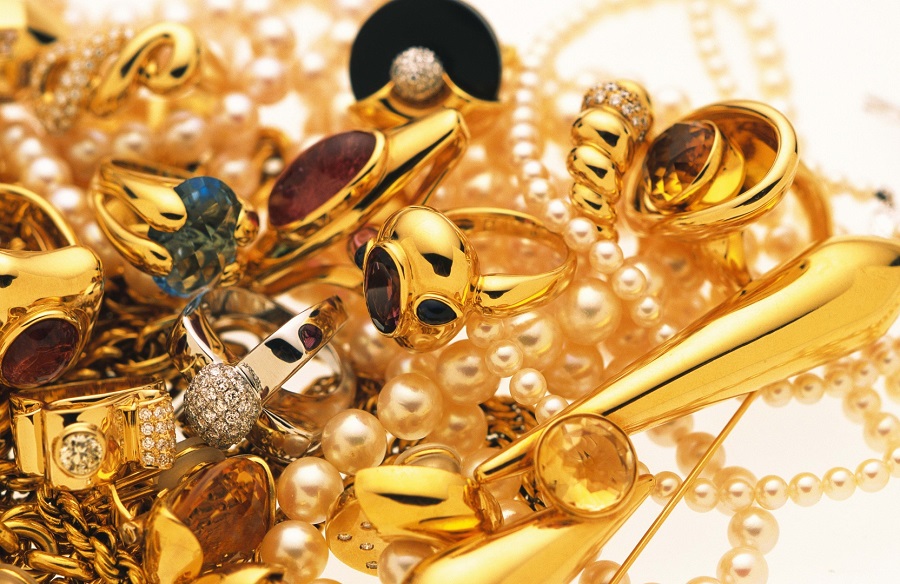 Gold rings, chains and pearls arranged closely together