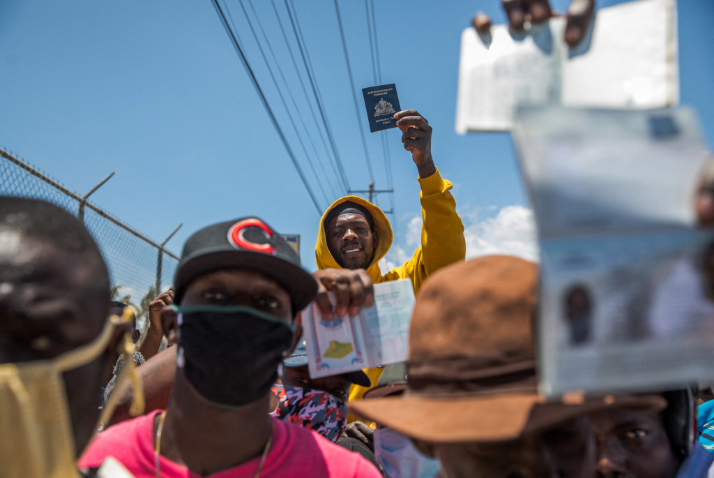 Haitian citizens hold up passports as they gather in front of the US Embassy in Tabarre, Haiti