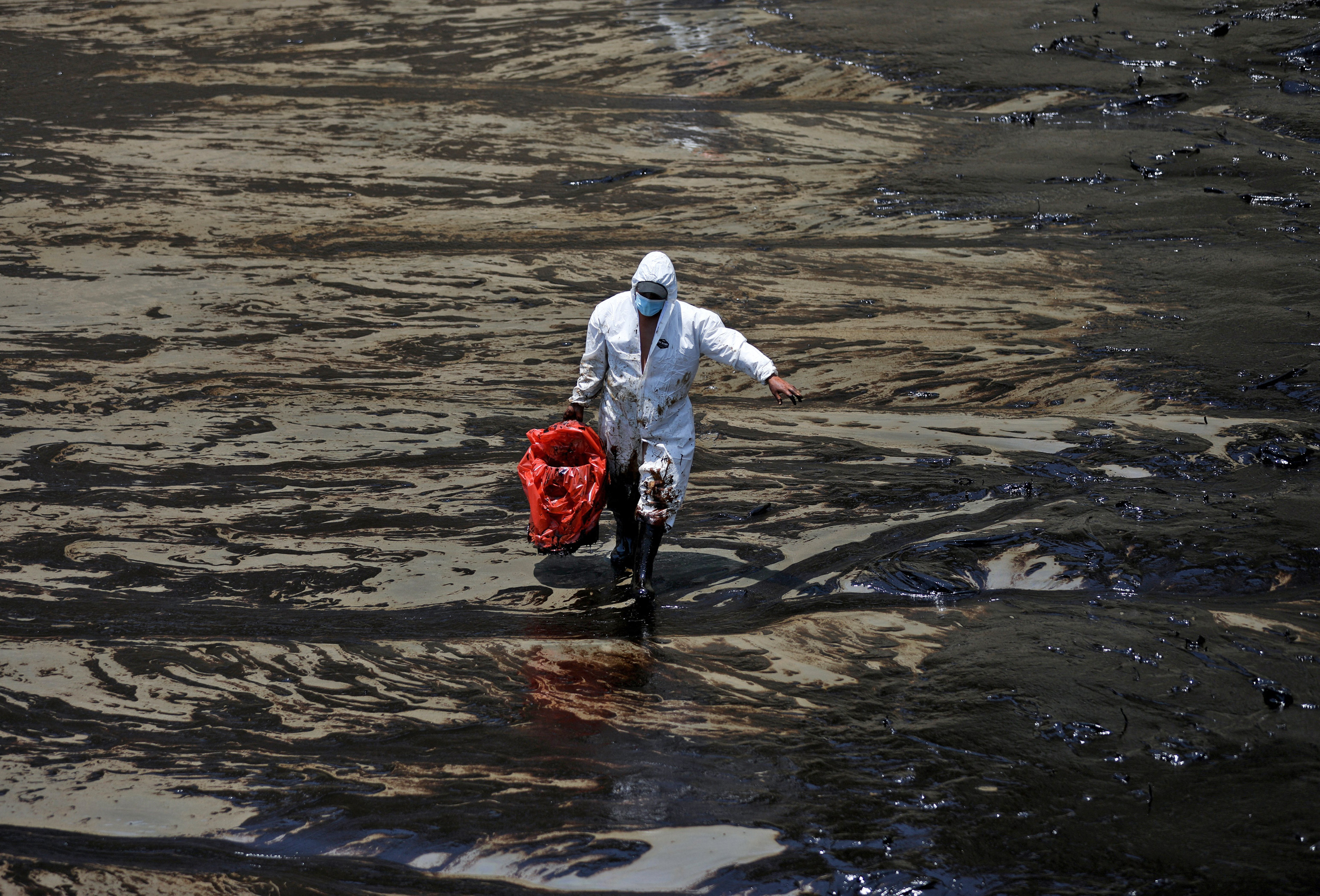 Image: Workers clean up an oil spill in Ventanilla