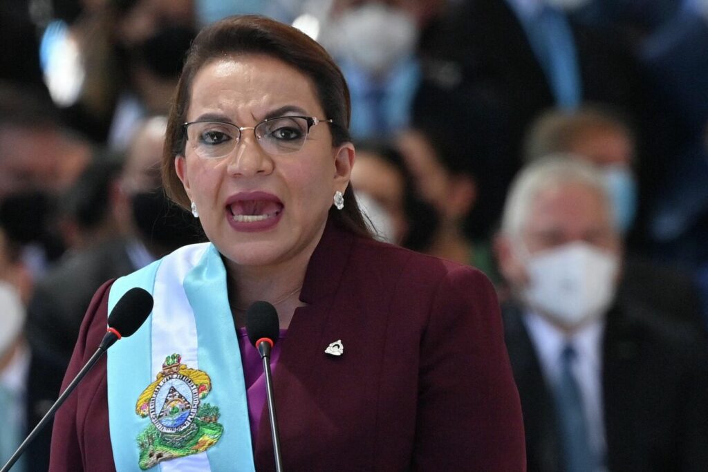 Xiomara Castro speaking at a podium with a sash