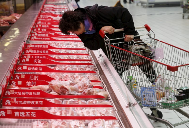 A customer chooses a meat product at Sun Art Retail Group's Auchan hypermarket store in Beijing