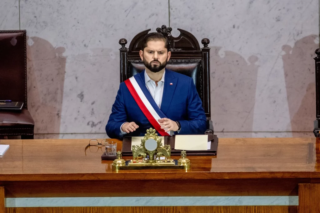 Man in suit and sash sitting at a desk