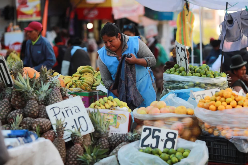 A market vendor selling fruit with price signs visible