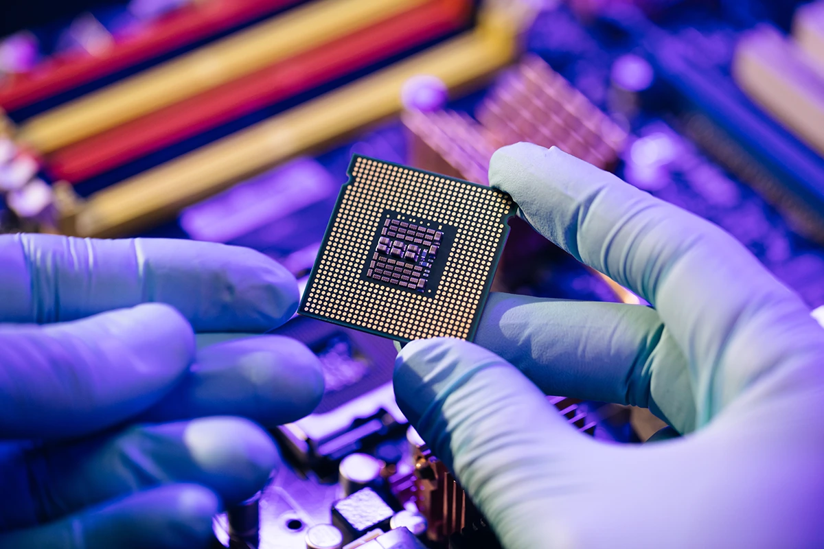 A semiconductor chip held over a circuit board, the contested heart of global supply chains