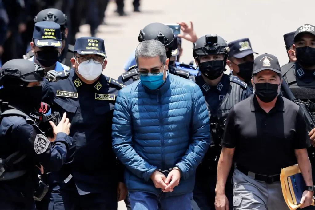 Man in handcuffs surrounded by police officers