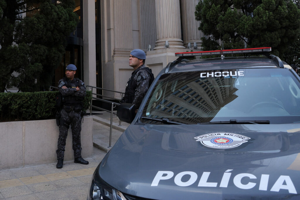 Brazilian police officers and police car outside a building