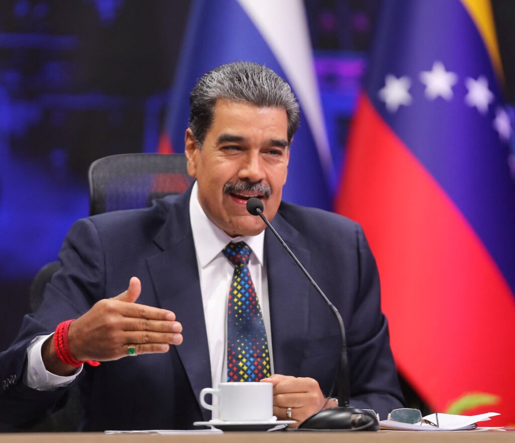 Man speaking at podium with Venezuelan flag in background