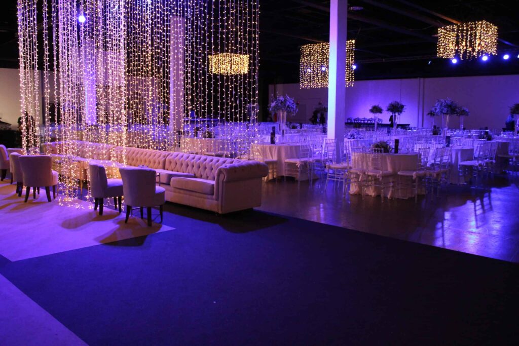 An elegant event space with string lights, tables, and seating.
