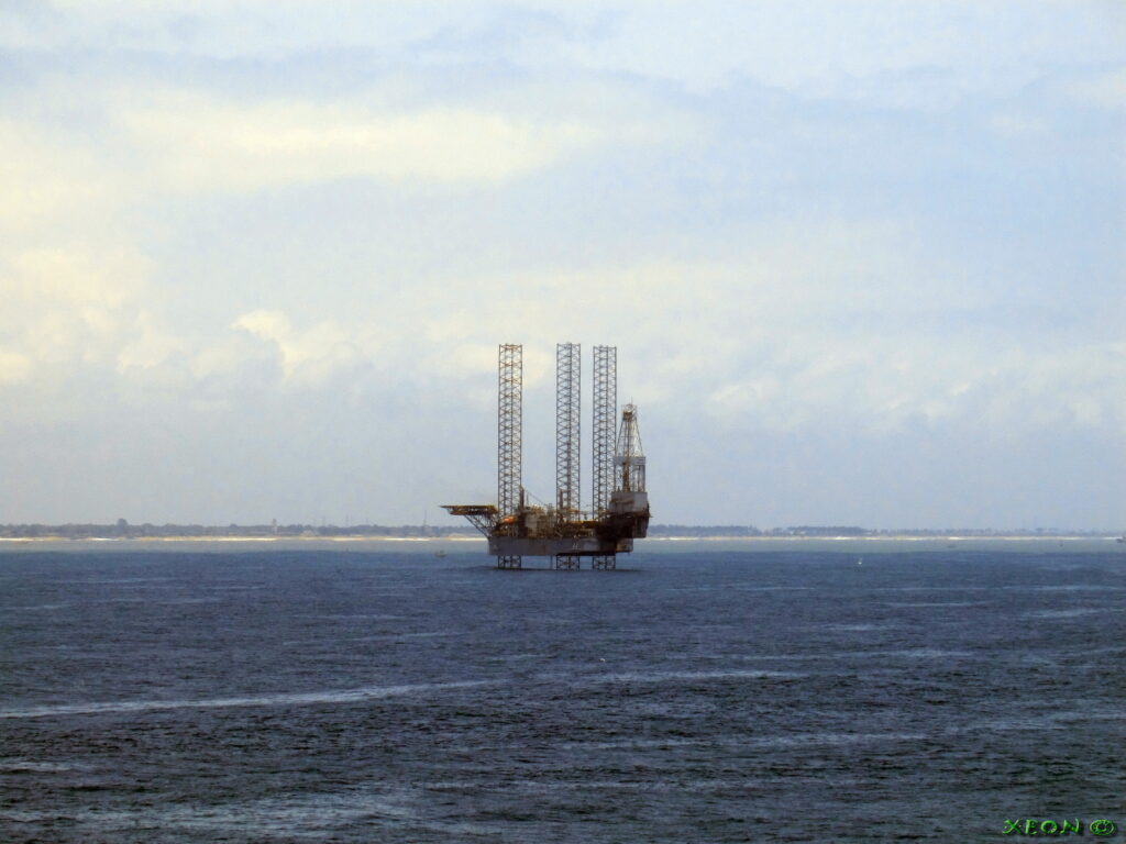 An offshore oil rig in the ocean under a cloudy sky.