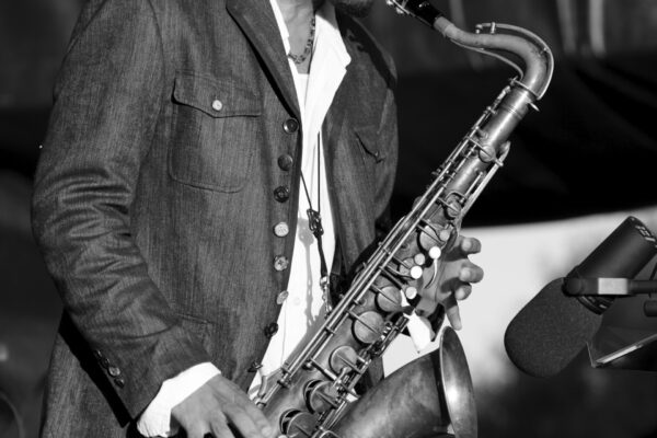 Man playing saxophone on stage with microphone