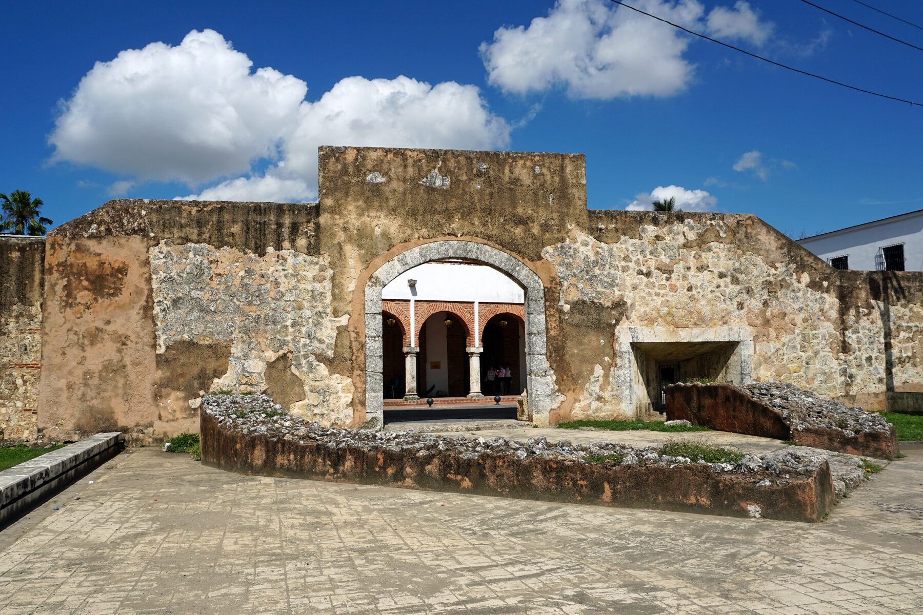 Old stone wall with archway under blue sky