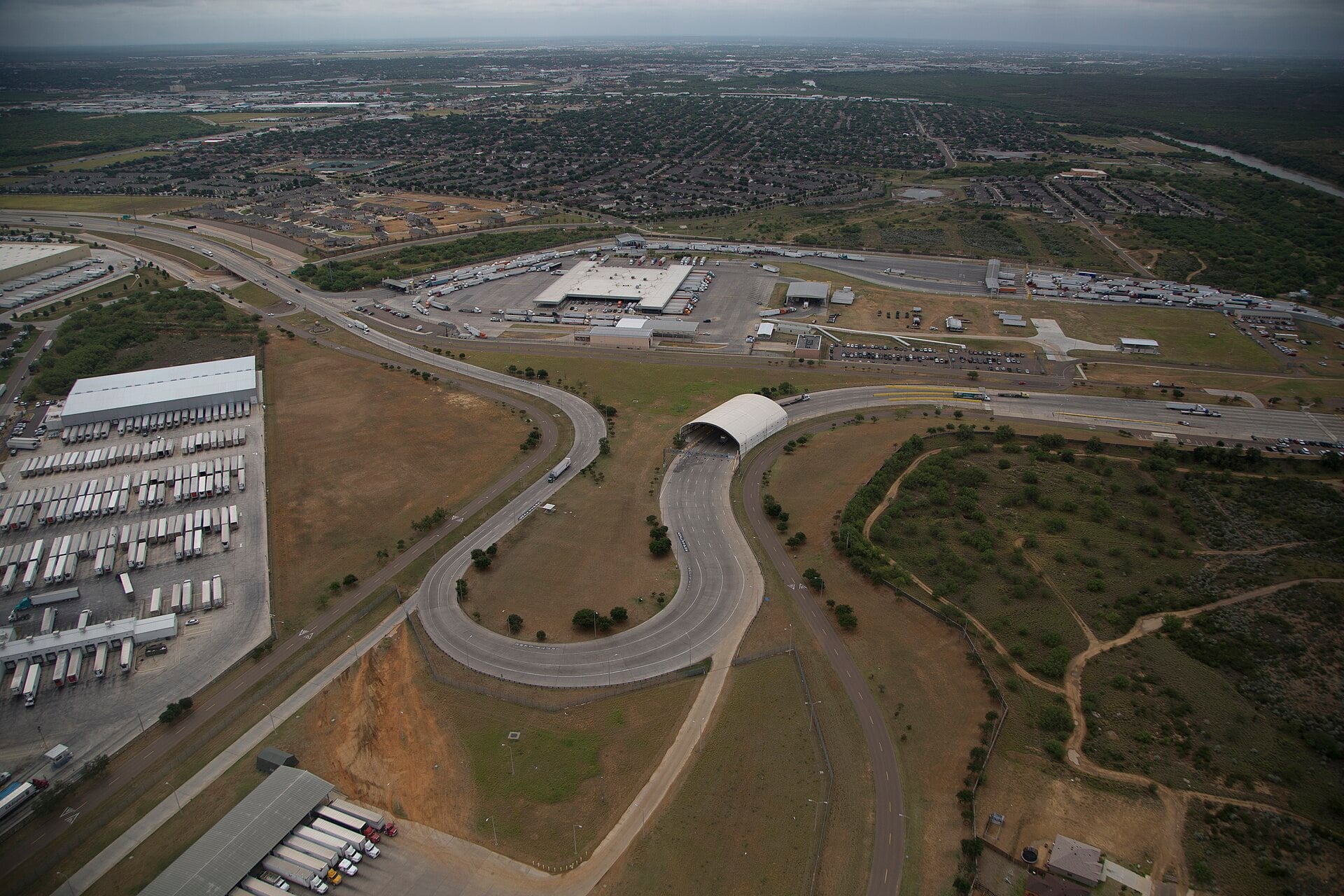 Cargo trucks queue at a US-Mexico border crossing, the trade artery at the heart of the USMCA.