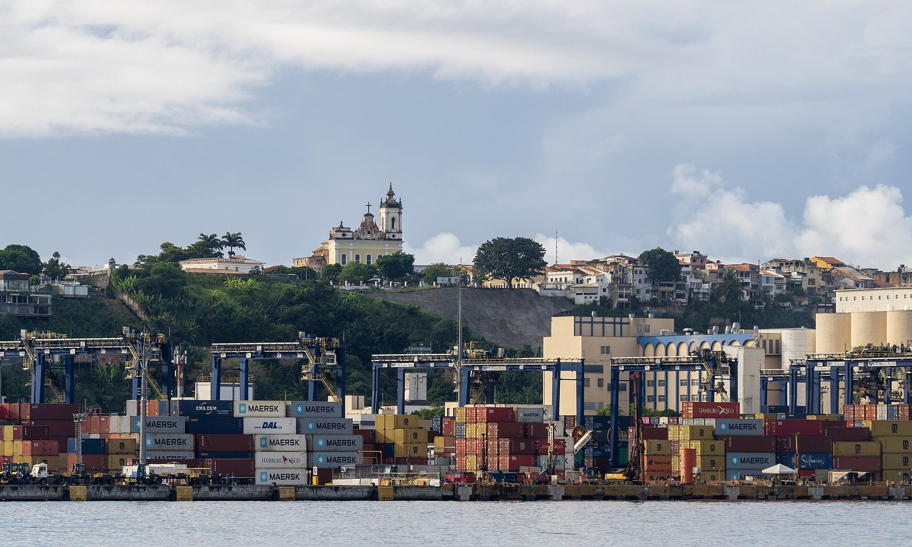 A container ship docked at the port of Santos, Brazil, its cargo silhouetted against the morning sky as global trade disruptions reshape Latin America's economic future.
